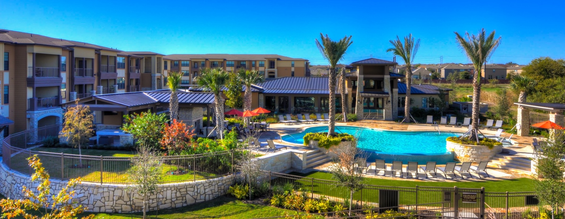 an aerial view of a building and a pool with many trees nearby